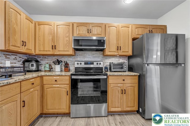 511 Lakeside Dr, Stroud Twp, PA 18301 - kitchen featuring light wood-type flooring, appliances with stainless steel finishes, backsplash, and light stone countertops