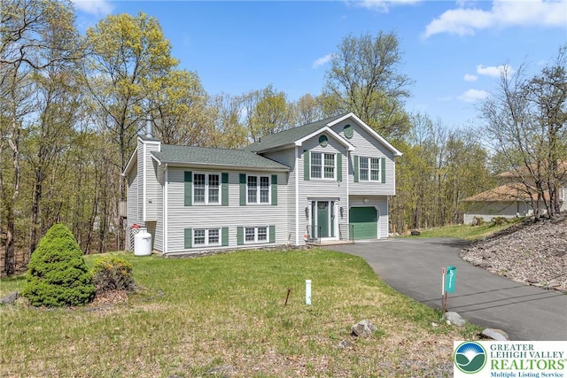 511 Lakeside Dr, Stroud Twp, PA 18301 - split level home featuring roof with shingles, aphalt driveway, a garage, a front yard, and a chimney
