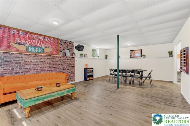 511 Lakeside Dr, Stroud Twp, PA 18301 - game room with baseboards, brick wall, a drop ceiling, and wood finished floors