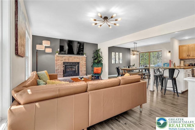 511 Lakeside Dr, Stroud Twp, PA 18301 - living room featuring a fireplace, light wood-type flooring, and a notable chandelier