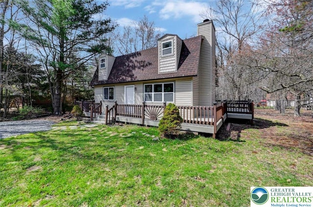 rear view of house featuring a lawn, a wooden deck, a shingled roof, and a chimney