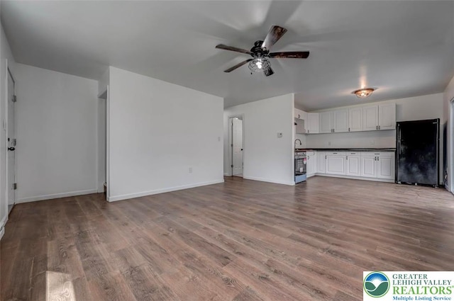 unfurnished living room with a ceiling fan, baseboards, and wood finished floors