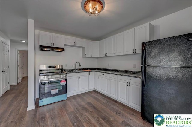 kitchen featuring freestanding refrigerator, white cabinetry, under cabinet range hood, and stainless steel electric range oven