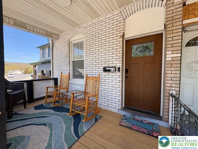 entrance to property with covered porch and brick siding