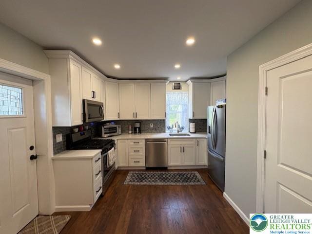 kitchen with a sink, appliances with stainless steel finishes, decorative backsplash, and light countertops