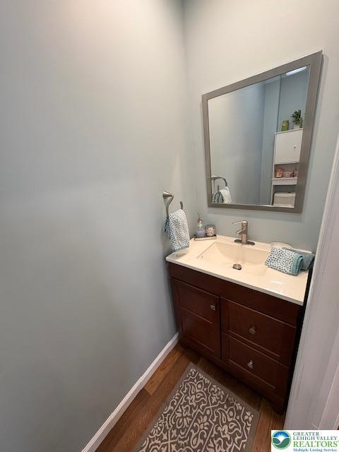 bathroom with baseboards, wood finished floors, and vanity