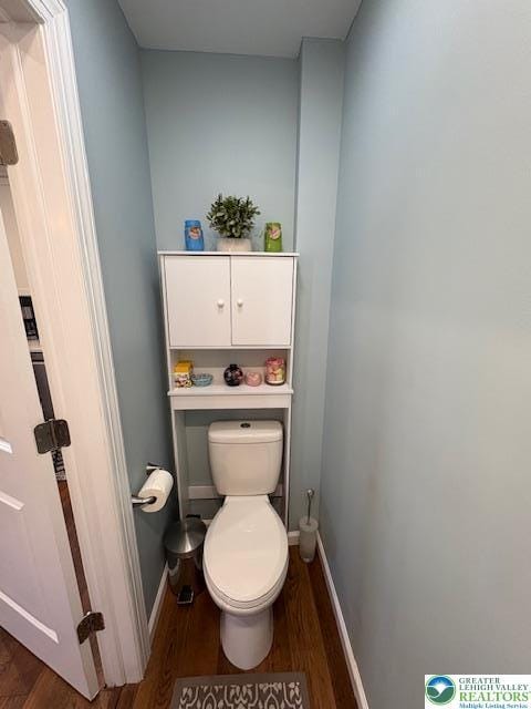 bathroom with baseboards, wood finished floors, and toilet