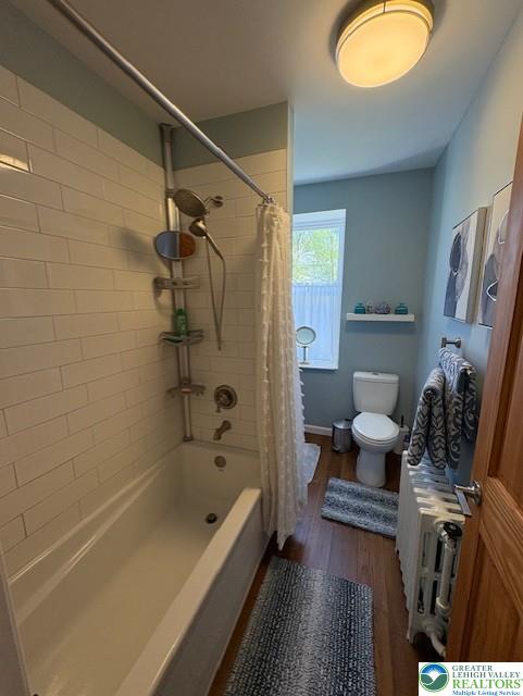 full bath featuring shower / bath combo, toilet, and wood finished floors