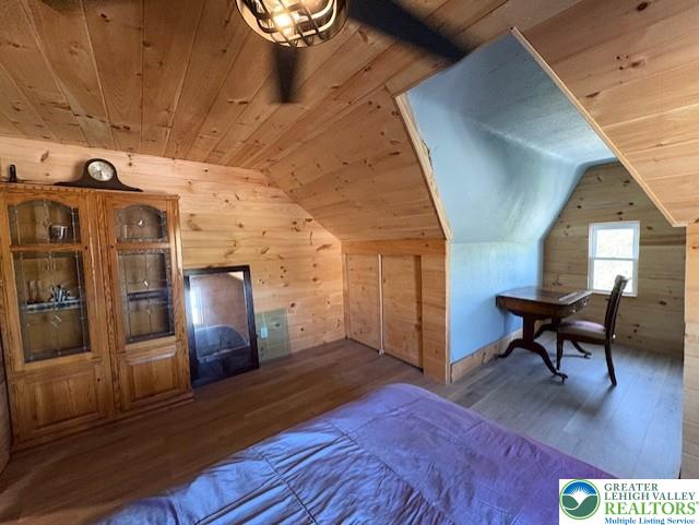 bedroom featuring wood walls, vaulted ceiling, wood ceiling, and wood finished floors