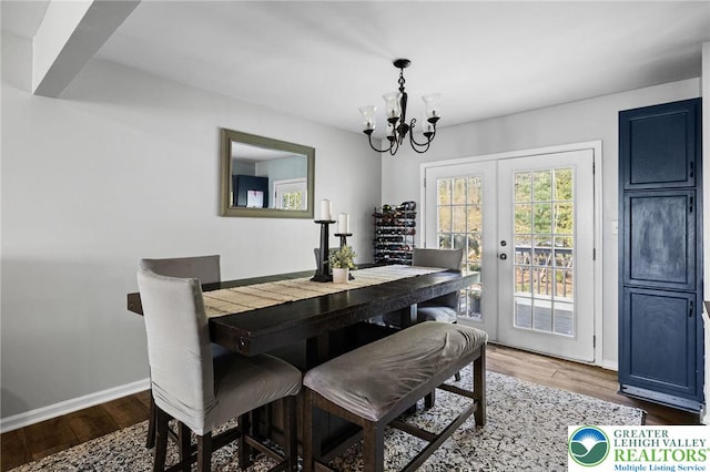 dining space with baseboards, wood finished floors, and a chandelier