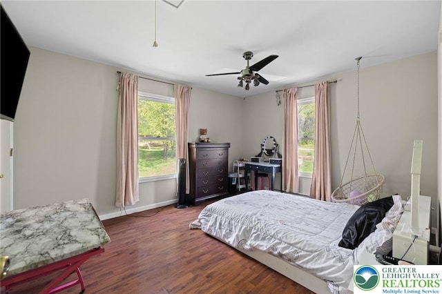 bedroom featuring a ceiling fan, baseboards, multiple windows, and wood finished floors