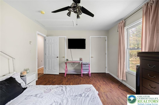 bedroom with ceiling fan, multiple windows, wood finished floors, and attic access
