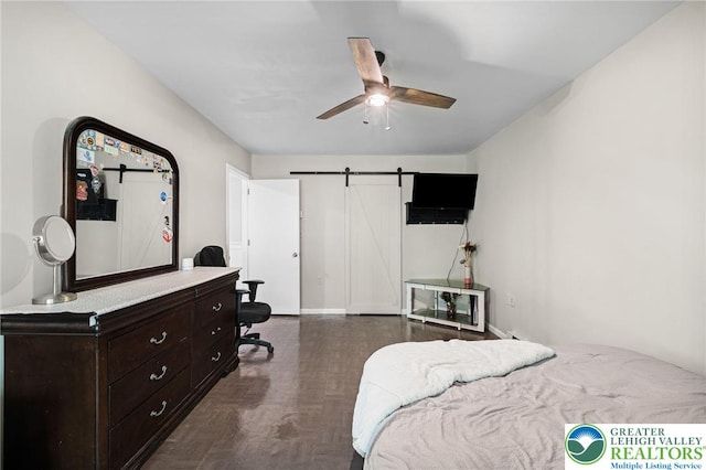 bedroom featuring ceiling fan, dark wood finished floors, and a barn door