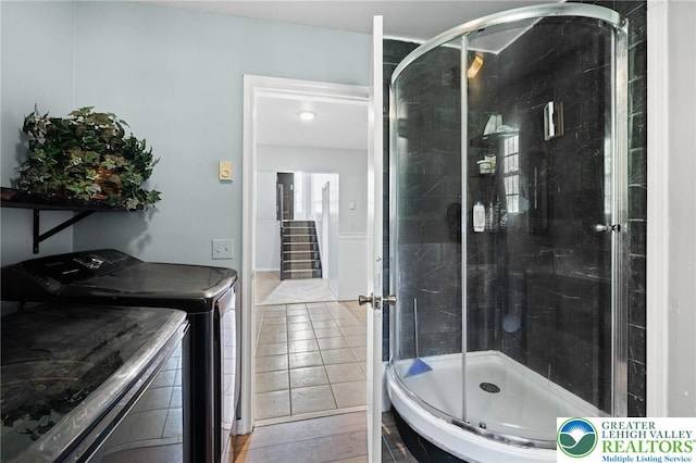 full bath featuring tile patterned flooring, washer and clothes dryer, and a shower stall