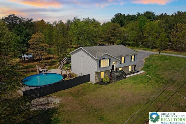 exterior space with fence, stairs, a fenced in pool, a yard, and a forest view