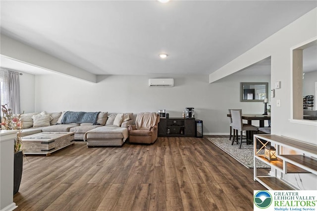 living area featuring dark wood-type flooring, baseboards, and a wall mounted AC