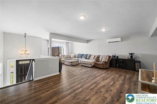 living room featuring dark wood-style flooring, a wall mounted AC, and an inviting chandelier