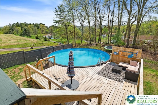 view of swimming pool featuring a fenced in pool, fence, a wooden deck, and outdoor lounge area