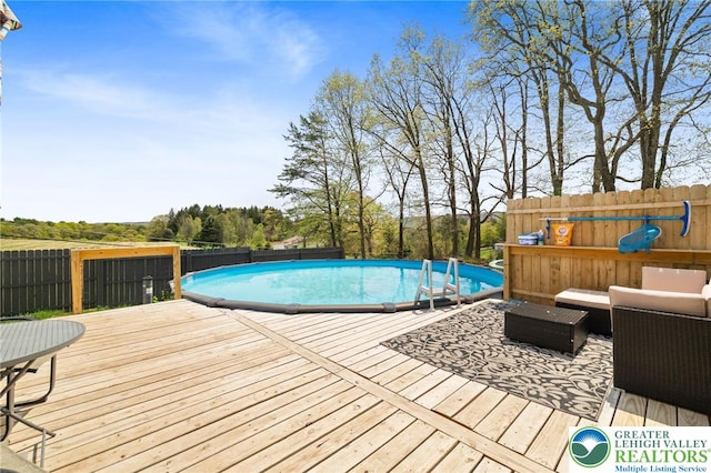view of pool with fence, a fenced in pool, a wooden deck, and outdoor lounge area