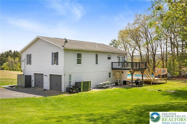 back of property with a lawn, a deck, an attached garage, and gravel driveway