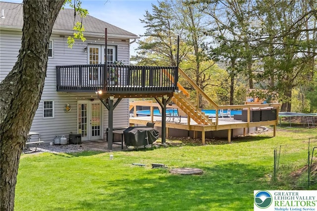 back of property with a yard, french doors, a trampoline, and a wooden deck