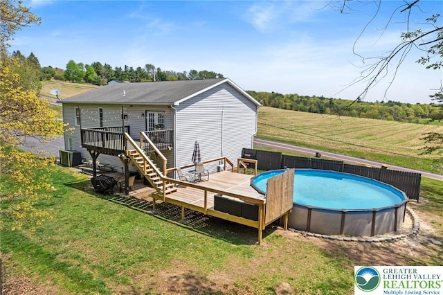 back of house with stairs, an outdoor pool, a yard, and a deck