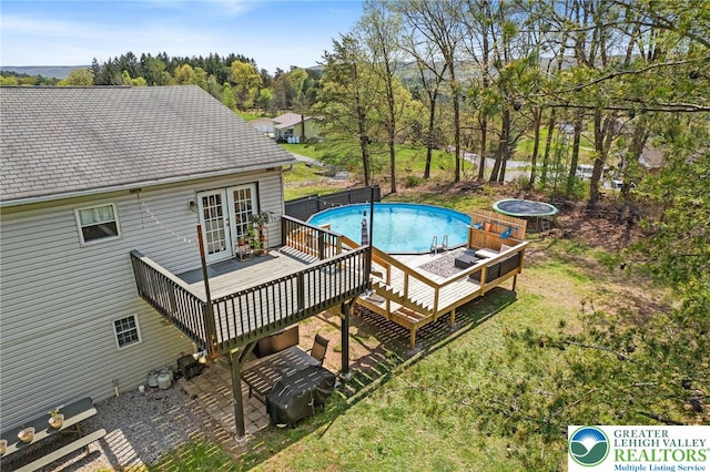 outdoor pool with french doors and a wooden deck