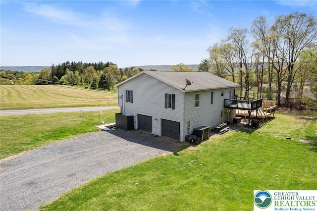 view of home's exterior with a lawn, a garage, a wooden deck, and gravel driveway
