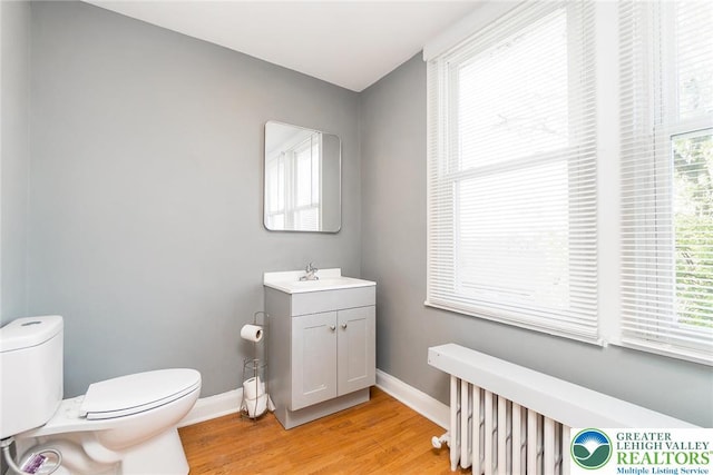 bathroom with baseboards, wood finished floors, toilet, and vanity
