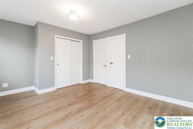 unfurnished bedroom featuring baseboards, light wood finished floors, and a closet