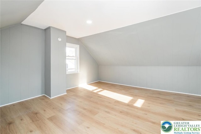 bonus room with baseboards, light wood-style flooring, and lofted ceiling