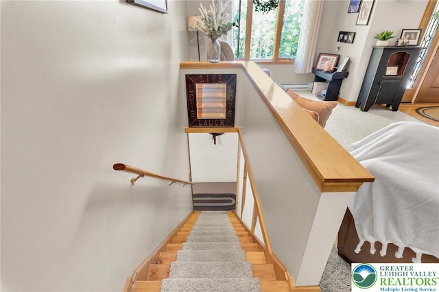 stairs with a baseboard heating unit and wood finished floors