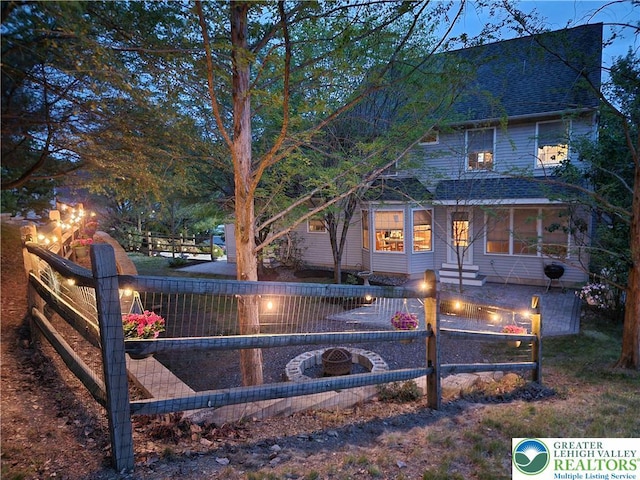 view of side of property featuring fence, roof with shingles, and an outdoor fire pit