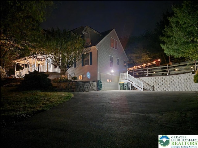 property exterior at twilight featuring stairway, an attached garage, and driveway