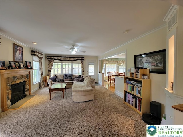 living room with crown molding, visible vents, a fireplace, baseboards, and ceiling fan