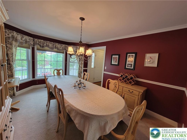 carpeted dining space with baseboards, a notable chandelier, and ornamental molding