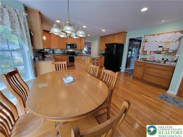 dining area with light wood-type flooring, recessed lighting, and a chandelier