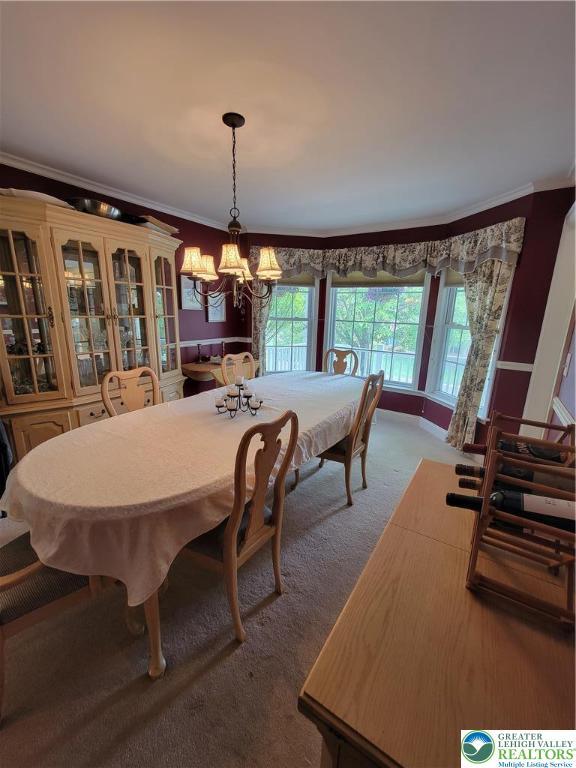 dining area with carpet flooring, a chandelier, and ornamental molding