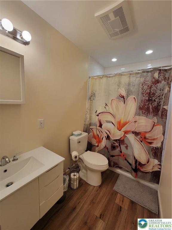 full bathroom with visible vents, vanity, wood finished floors, toilet, and a shower with shower curtain