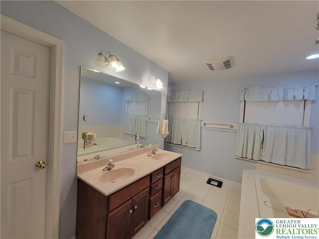 full bathroom featuring visible vents, double vanity, a bath, tile patterned floors, and a sink