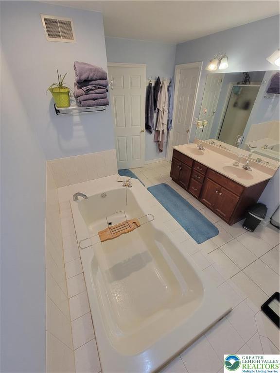 bathroom featuring a sink, double vanity, visible vents, a garden tub, and a stall shower