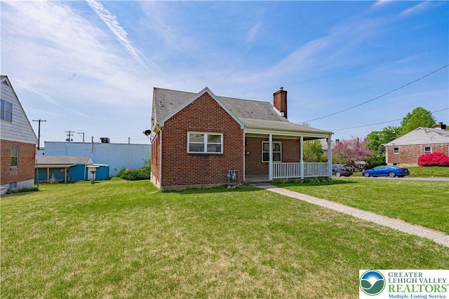 bungalow featuring covered porch, brick siding, a chimney, and a front lawn