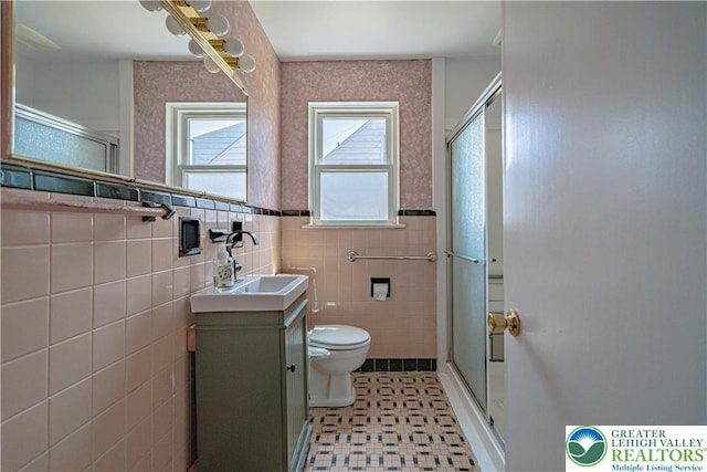 full bath featuring toilet, vanity, tile walls, and a shower stall