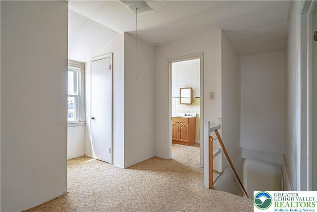 hall with light colored carpet, an upstairs landing, and lofted ceiling