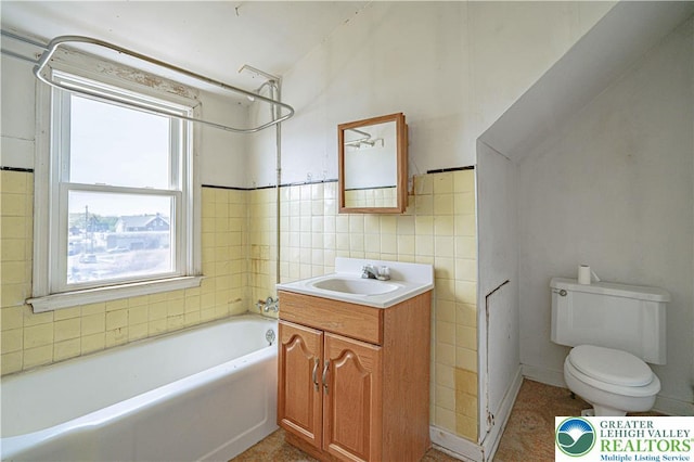 full bathroom with a tub, toilet, vanity, and a healthy amount of sunlight