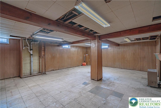 below grade area with a wealth of natural light, wood walls, and visible vents