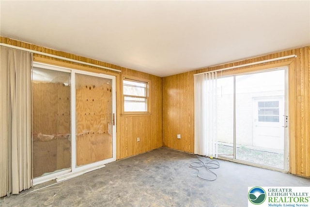 carpeted spare room with wood walls