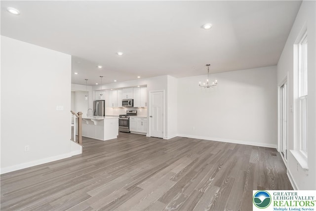 1022 Watson Ct, Upper Macungie Twp, PA 18051 - unfurnished living room with a chandelier, wood finished floors, baseboards, recessed lighting, and a sink