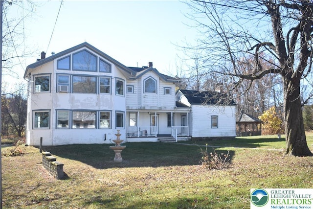 view of front of home featuring covered porch, stucco siding, a front lawn, and a chimney