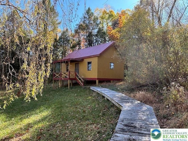 back of house featuring metal roof and a yard